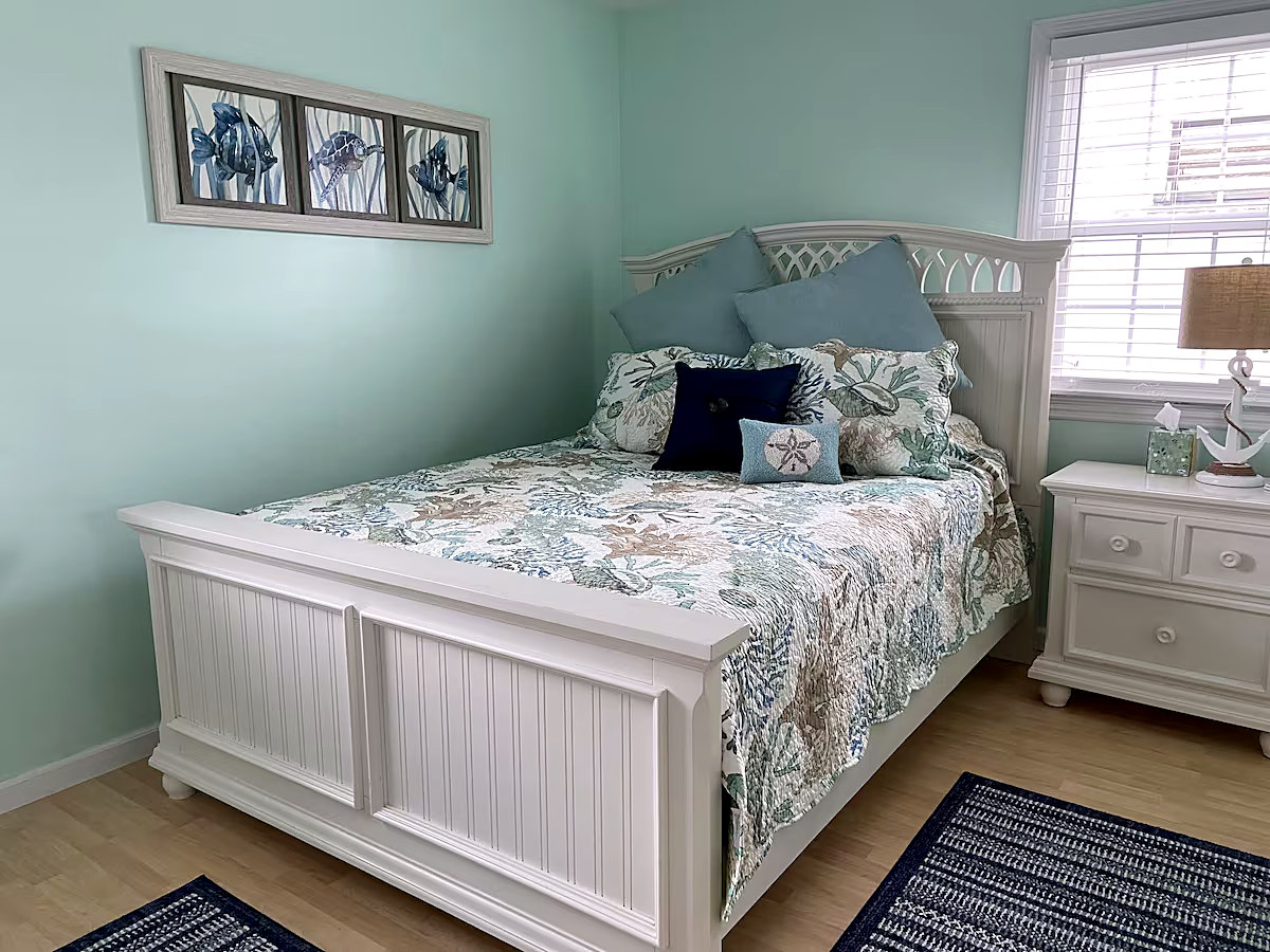 Queen bedroom with seafoam walls and a coral-print comforter